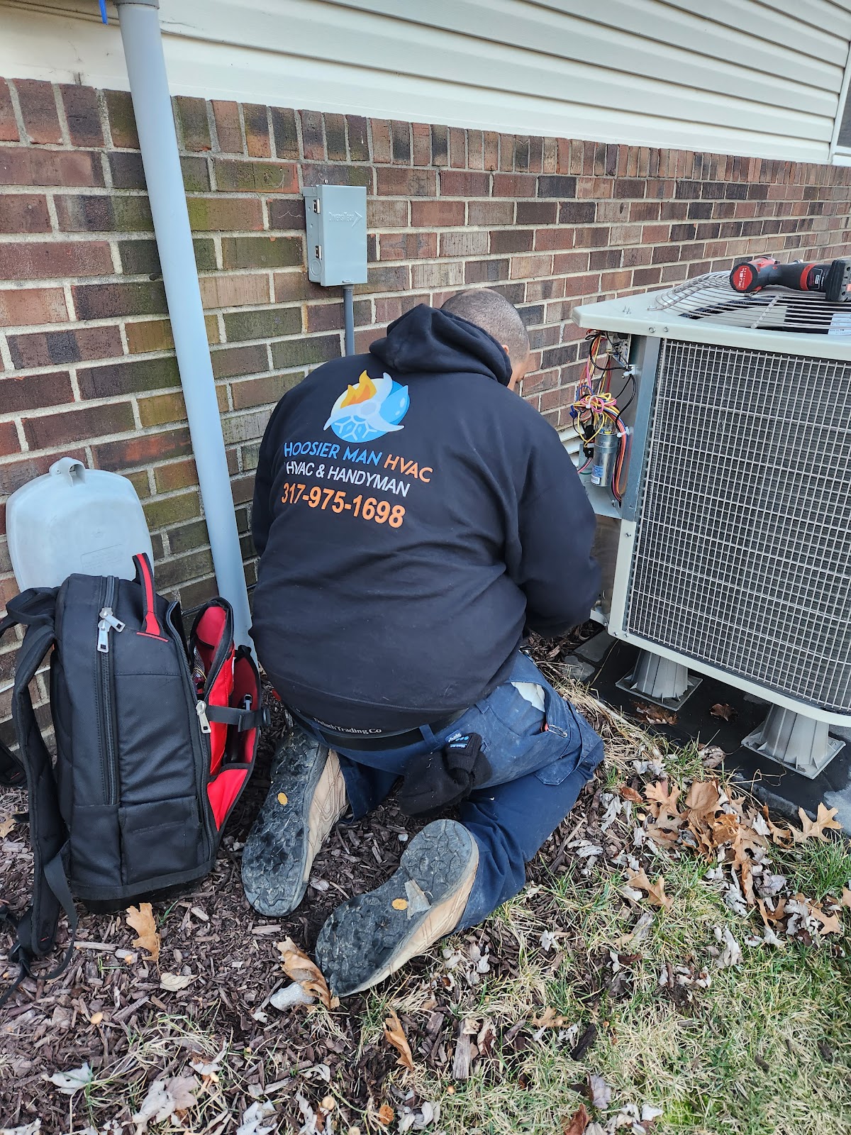 A Hoosier Man tech in the company hoodie working on an outdoor AC unit