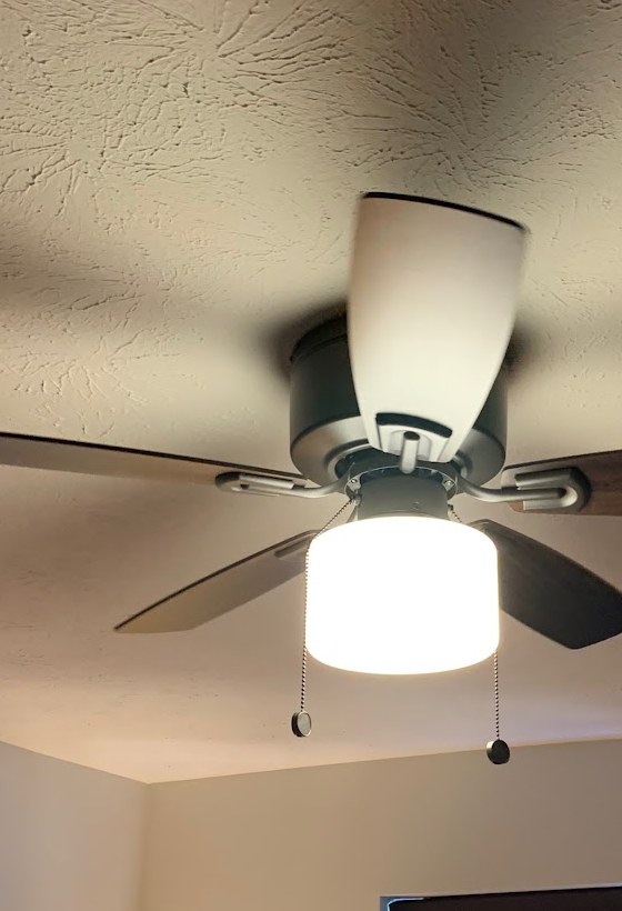A new ceiling fan and light installed in a bedroom